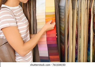 Young Woman Choosing Fabric For New Curtains In Shop