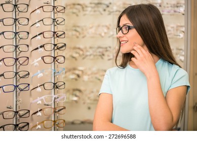 Young Woman Is Choosing A Glasses In Optician Store.