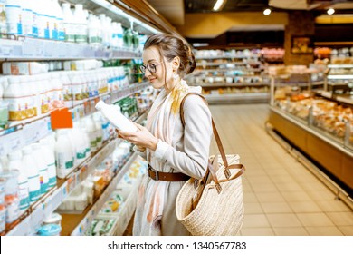 Young Woman Choosing Milk Standing Near The Shelves With Dairy Products In The Supermarket