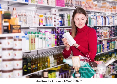 Young woman is choosing modern hair care and body products for her in the store