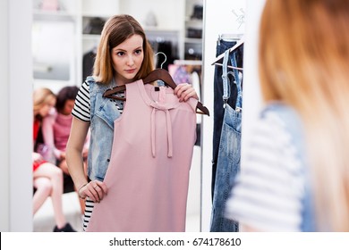 Young woman choosing new pink dress in a fashion boutique - Powered by Shutterstock