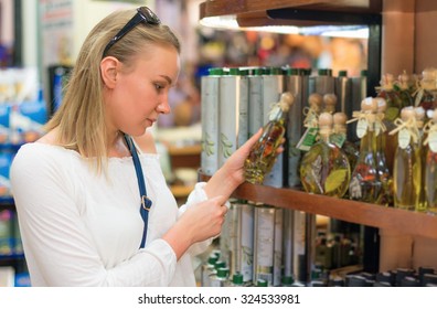 Young Woman Choosing Olive Oil In Grocery Store.