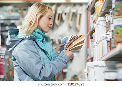 Young Woman Choosing Paint Using Color Samples During Hardware Shopping In Home Improvement Store Supermarket