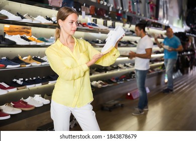 Young Woman Choosing Sneakers In Streetwear Store