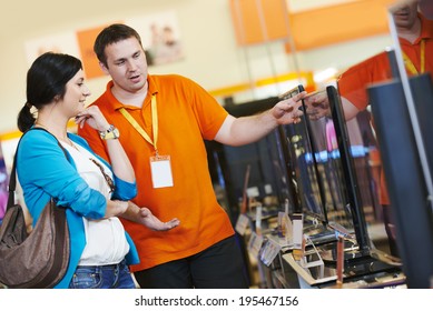 Young Woman Choosing Tv Set With Shop Assistant In Home Appliance Shopping Mall Supermarket