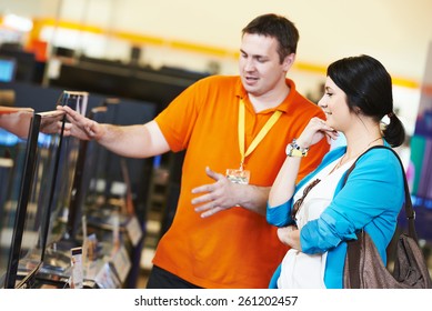 Young Woman Choosing Tv Set With Shop Assistant In Home Appliance Shopping Mall Supermarket