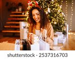 Young woman with christmas presents by the christmas tree. Winter holidays.