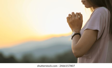 young woman clasped her hands together in prayer asking for forgiveness from God based on her Christian beliefs and faith in God teachings. concept prayer and intercession according beliefs about God - Powered by Shutterstock