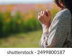 Young woman clasping her hands together and praying to god for blessings according to her belief and faith in god. Concept of praying to god according to Christian belief.