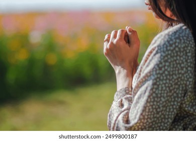 Young woman clasping her hands together and praying to god for blessings according to her belief and faith in god. Concept of praying to god according to Christian belief.