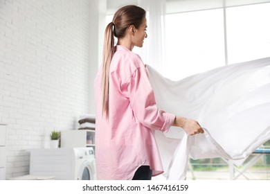 Young Woman With Clean Bedsheet Indoors. Laundry Day
