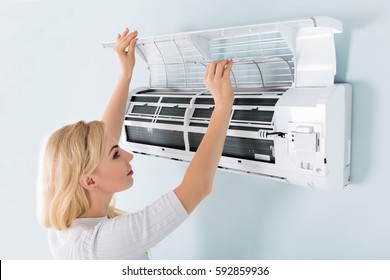 A Young Woman Cleaning Air Conditioning System At Home