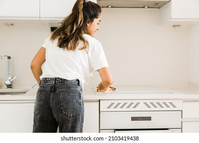 young woman cleaning the ceramic hob in kitchen