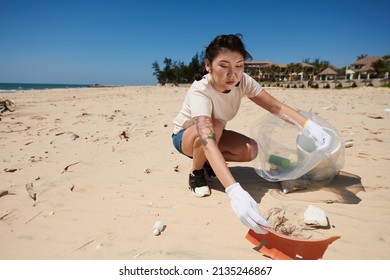 Young Woman Cleaning Coastal Zone And Putting Spilled Garbage In Big Plastic Bag