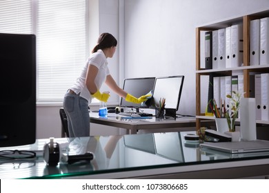 Young Woman Cleaning Computer With Rag In Office