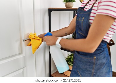 Young Woman Cleaning Doorknob At Home