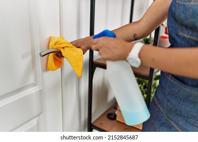 Young Woman Cleaning Doorknob At Home