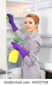 Young Woman Cleaning Empty Fridge With A Sponge