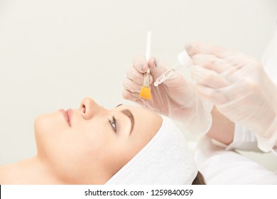 Young Woman Cleaning Face Skin In Salon. Retinol Peel With Brush. Acid Organic Peeling.