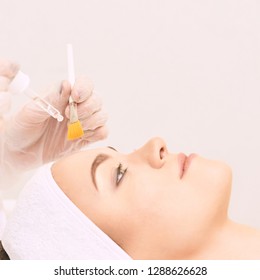 Young Woman Cleaning Face Skin In Salon. Retinol Peel With Brush. Acid Organic Peeling.