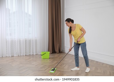 Young Woman Cleaning Floor With Mop In Empty Room