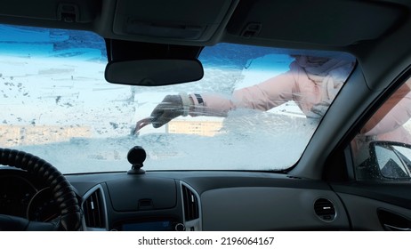 Young Woman Cleaning Frozen Windshield With Ice Scraper, Winter Season