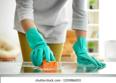 Young Woman Cleaning Glass Table At Home