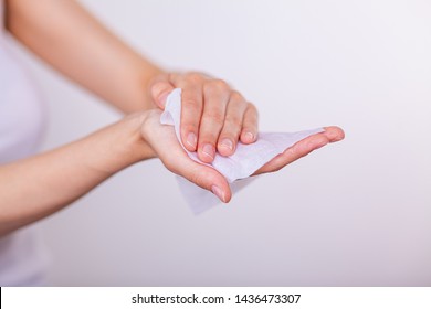 Young woman cleaning hands with wet wipes, white