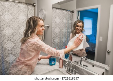 Young Woman Cleaning Her Bathroom Mirror - Wiping Glass Cleaner Off Of Mirror