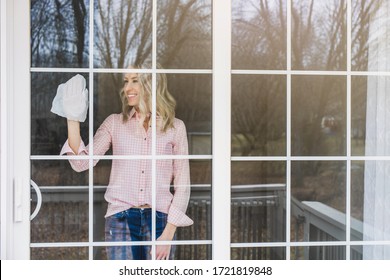 Young Woman Cleaning Her Sliding Door Windows With Paper Towel 