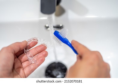 Young woman cleaning an invisible teeth aligner with a brush