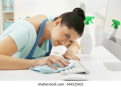 Young Woman Cleaning Keyboard In Office