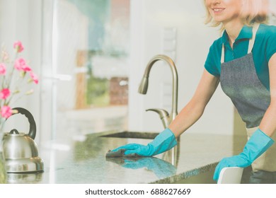 Young Woman Is Cleaning Marble Counter Top In Blue Rubber Gloves