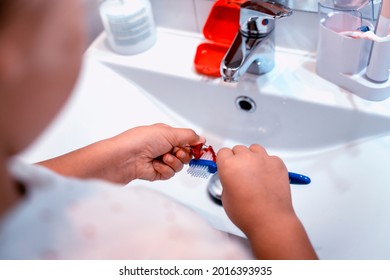 A Young Woman Cleaning The Prognathism Appliance With A Toothbrush In The Bathroom. Dental Care And Hygiene Concept