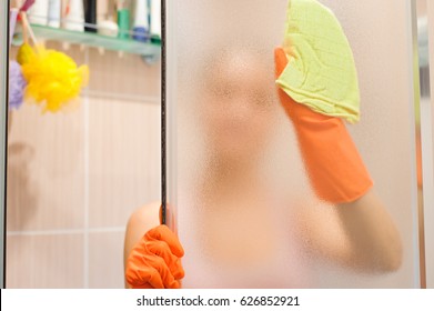 Young Woman Cleaning Shower Door