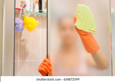 Young Woman Cleaning Shower Door