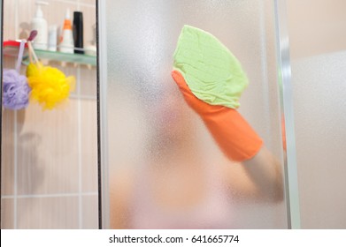 Young Woman Cleaning Shower Door