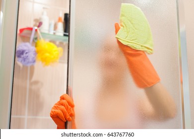 Young Woman Cleaning Shower Door