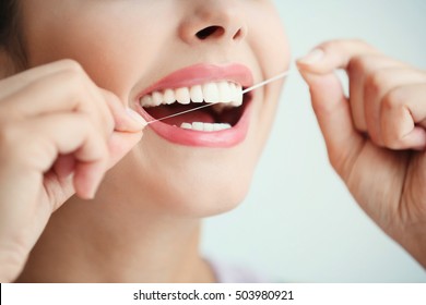 Young woman cleaning teeth with dental floss, close up - Shutterstock ID 503980921