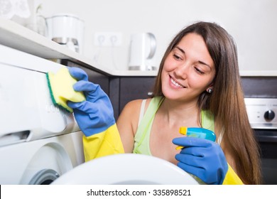 Young Woman Cleaning Washing Machine At Home Kitchen
