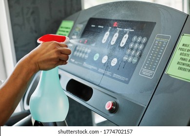 Young Woman Cleaning And Weeping  Fitness Gym Equipment With Sprayer 