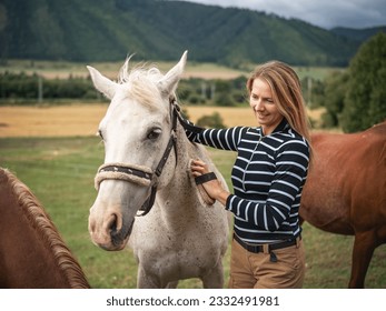 Young woman cleaning white gray horse with brush, her head next to animal - Powered by Shutterstock