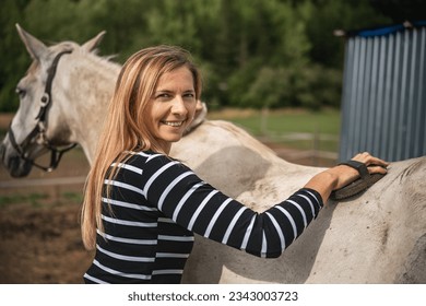 Young woman cleaning white gray horse with brush - Powered by Shutterstock
