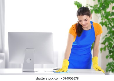 Young woman cleaning workplace with computer monitor in the office - Powered by Shutterstock