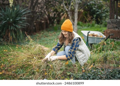 Young woman cleans the garden from dried plants using pruning shears, autumn garden cleaning concept - Powered by Shutterstock