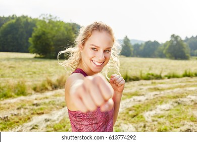 Young woman clenching a fist while practicing boxing in the nature