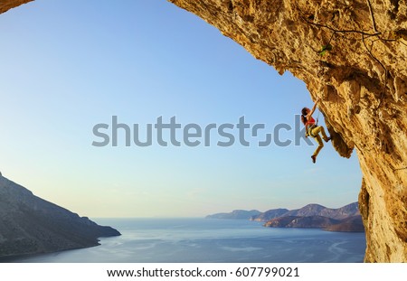 Young woman climbing challenging route in cave at sunset