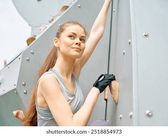 Young woman climbing an indoor rock climbing wall, smiling confidently while holding onto a grip, dressed in athletic wear - Powered by Shutterstock