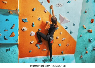 Tânără femeie urcând pe perete practica în sala de gimnastică, vedere din spate, fotografie de stoc