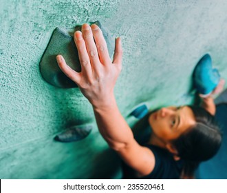 Young Woman Climbing Up On Wall In Gym, Focus On Hand